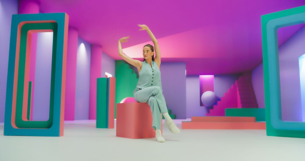Portrait of Young Woman Sitting in Geometric Abstract Environment, Dancing with Hypnotic Graceful Movements. Fashionable Female Dancer Practicing Her Routine in Colorful Studio.