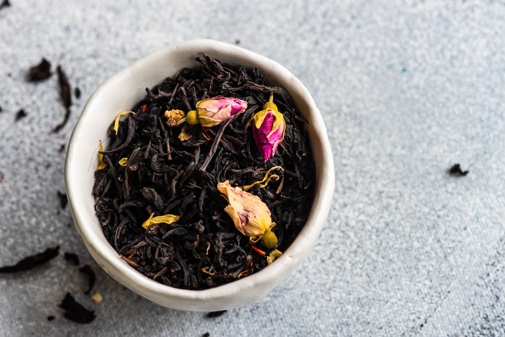 Rose bud loose leaf tea in bowl on stone background