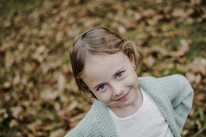 Smiling girl between meadow with dry leaves