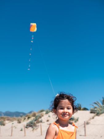 Toddler girl playing with kite on sandy beach