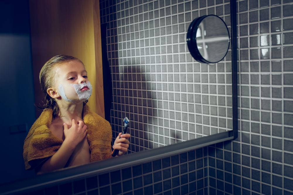 Boy shaving in bathroom with mirror