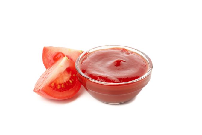 Glass bowl with tomato sauce isolated on neutral background