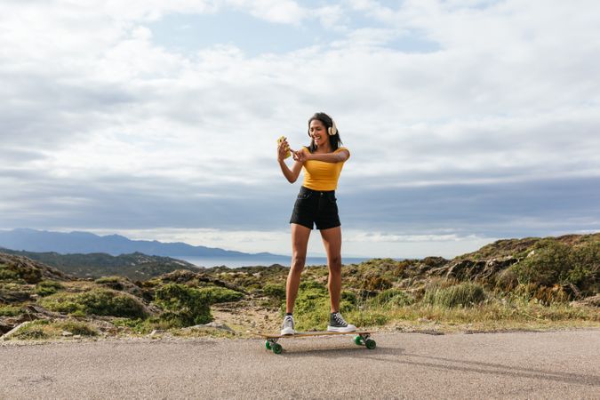 Smiling woman on longboard and taking selfie