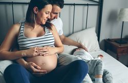 Pregnant woman with her husband looking son