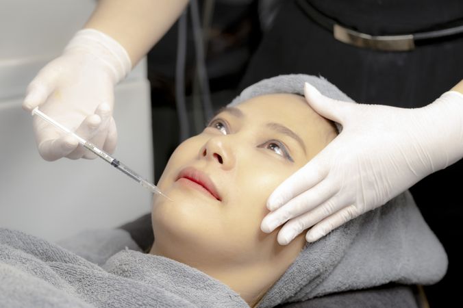 Experts perform injections for chin augmentation and anti-aging facials on young women, beauty clinics.
