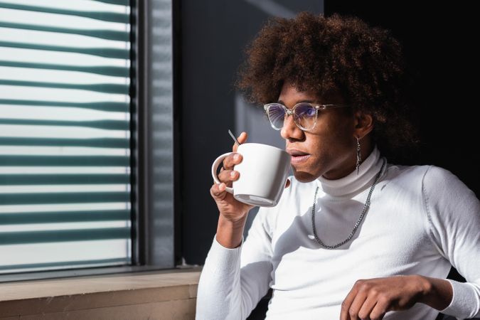 Pensive young Black man drinking coffee and looking away in cafe