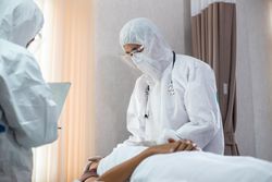 Emergency doctor in PPE checking vitals of patient