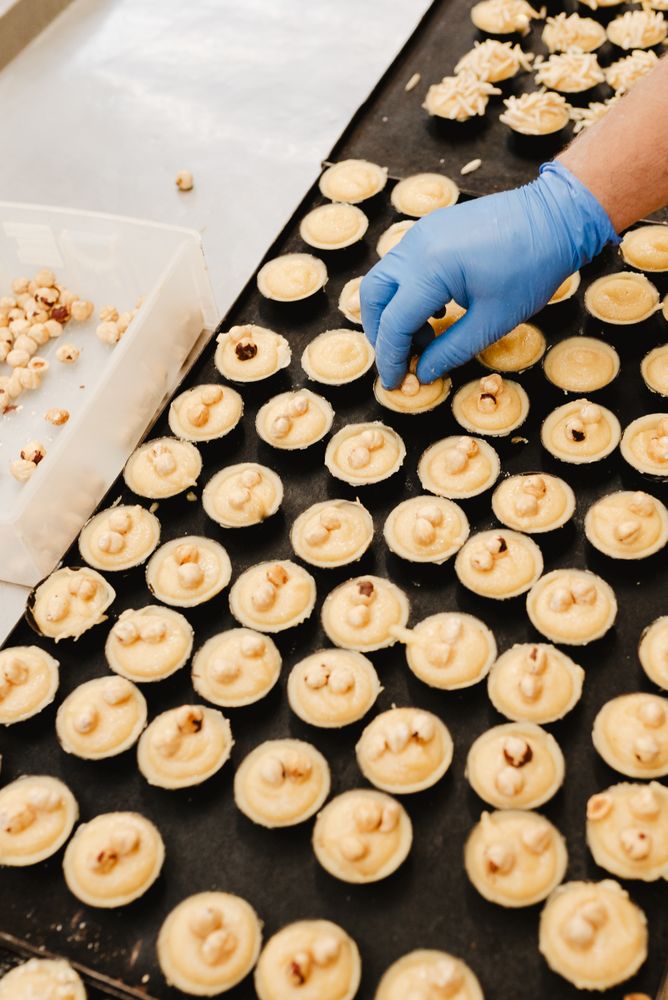 Crop confectioner decorating patisserie with nuts