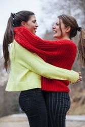 Smiling women in sweaters hugging in park