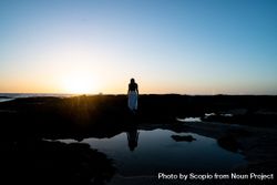 Woman standing on rock near body of water during sunset 4jAAX5