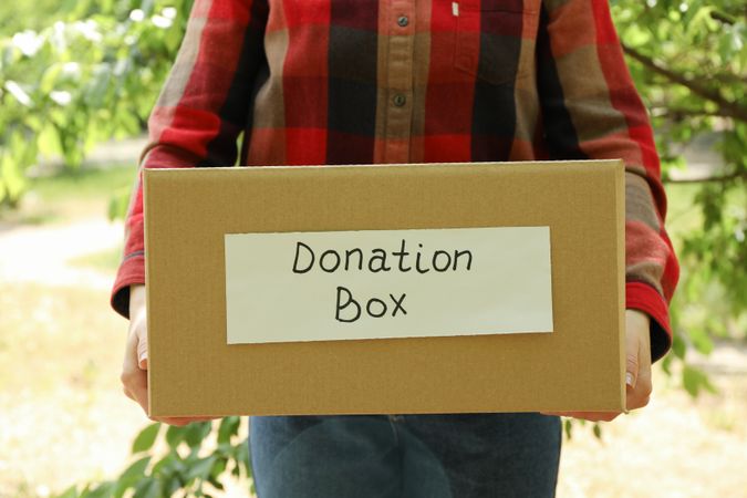 Woman holding donation paper bag outdoor. Volunteer