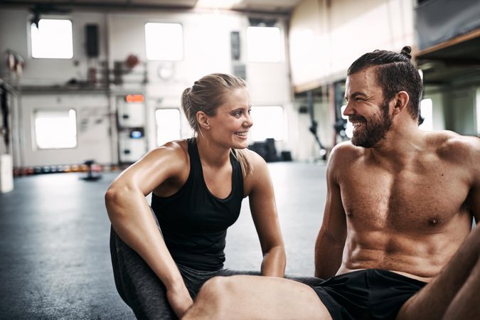 Man and woman smiling together on gym floor