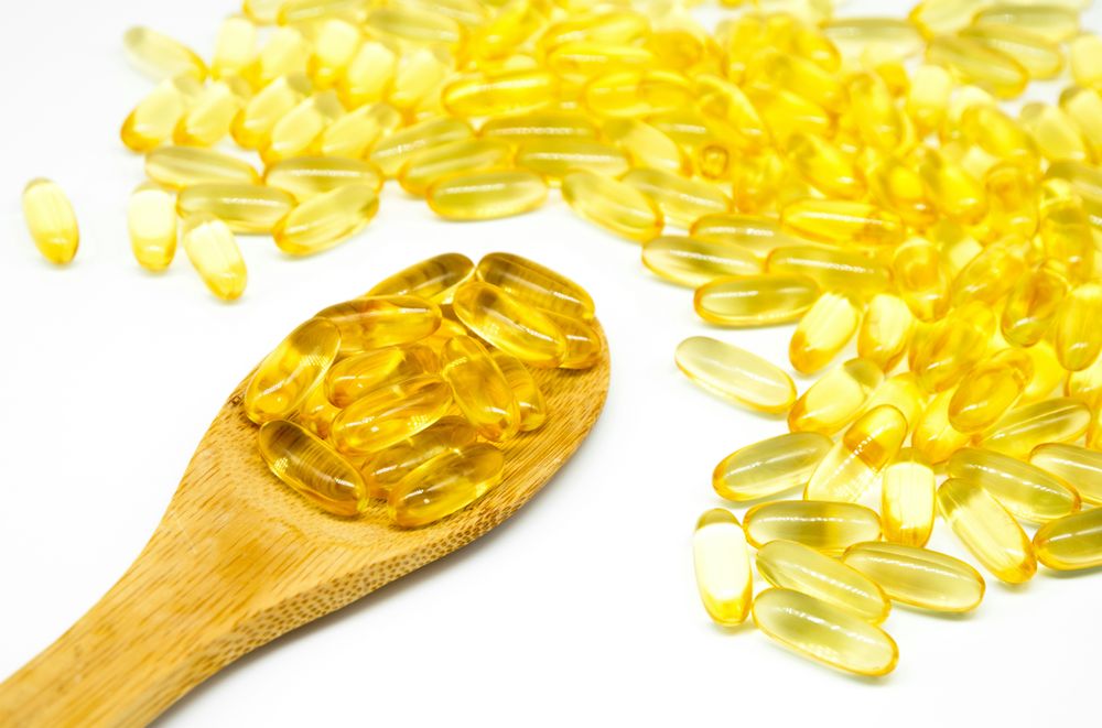 Fish Oil Capsules on Wooden Spoon and Pile