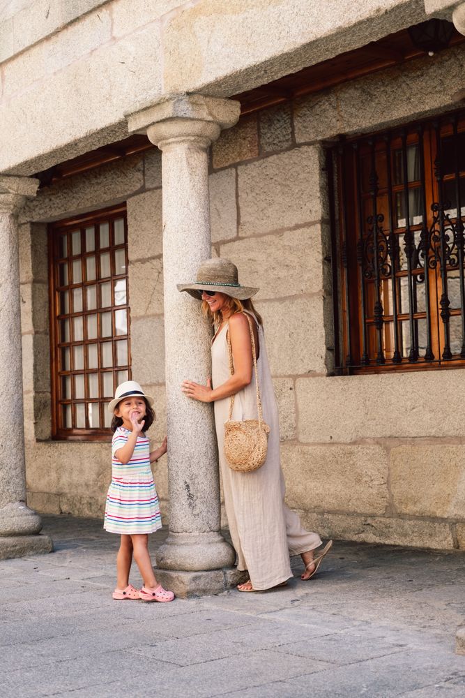 Mother and daughter walking in street along ancient building