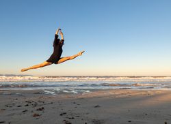 Woman jumping near water on shore