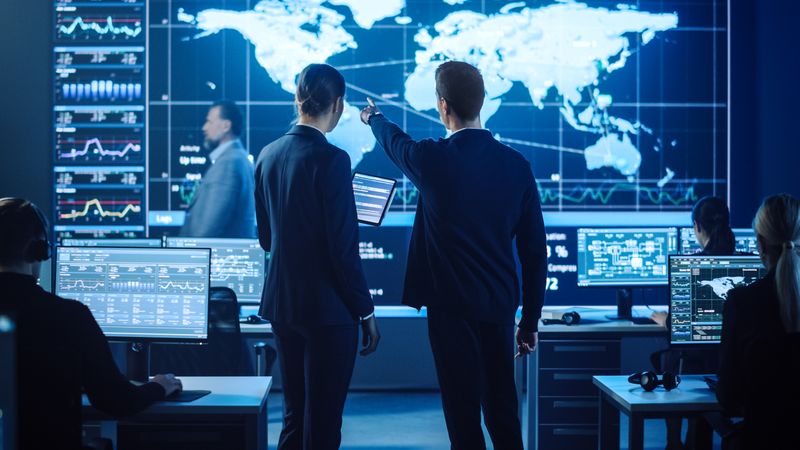 In a Modern Control Room, Diverse Professionals Collaborate, Analyzing Global Data on Large Screens to Optimize Cybersecurity Strategies and Decision-making Processes.