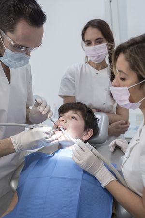 A portrait of dental team team working on young patient, vertical