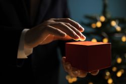 Businessman holding Christmas gift near tree