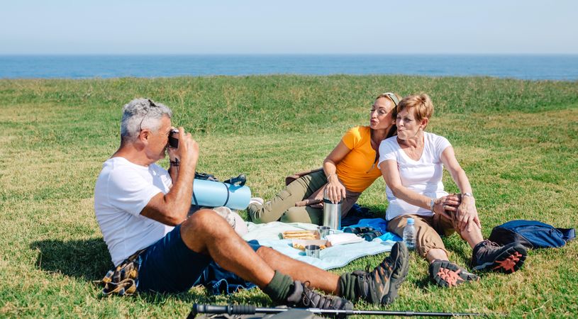 Man taking photo of his wife and daughter on scenic picnic