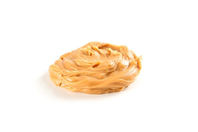 Creamy peanut butter isolated on light background. A traditional product of American cuisine