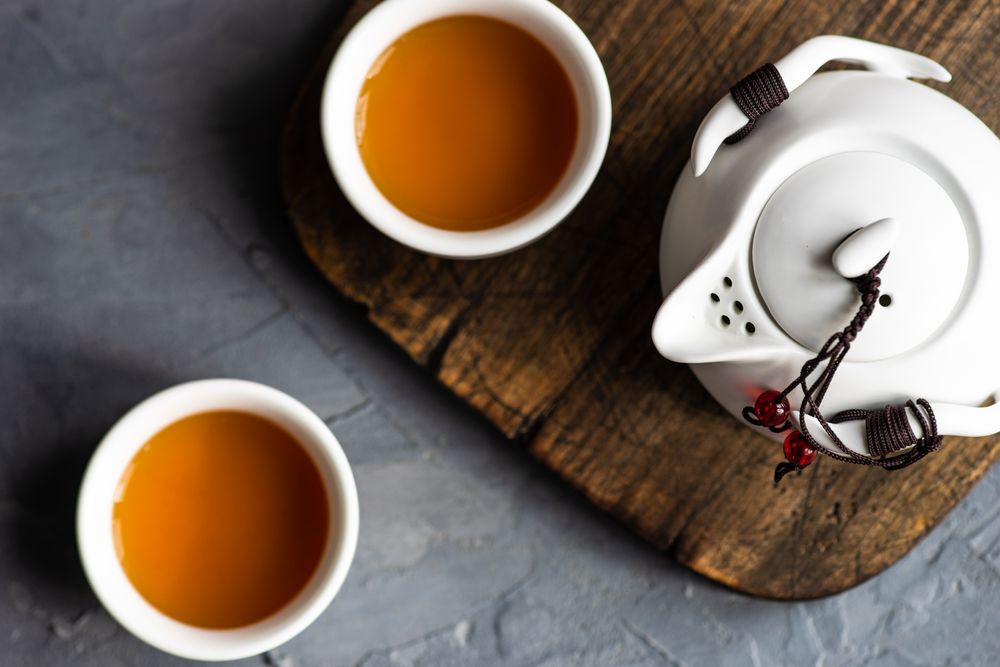 Teapot and cup with tea on grey counter with copy space