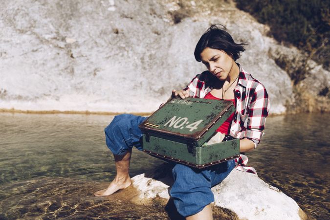 Woman with picnic case on rock in water