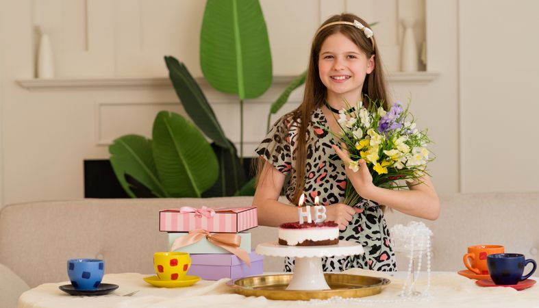 Girl enjoying birthday with flowers, cake and presents
