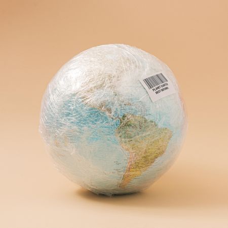 Earth in plastic wrap with bar code bag on beige background