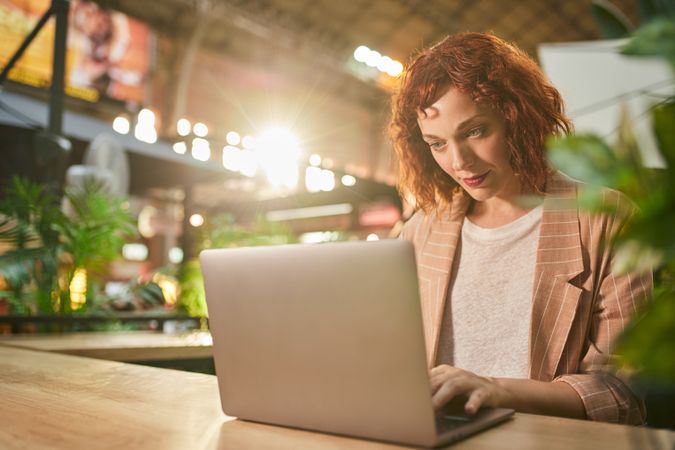 Cheerful young woman working on laptop in cafe
