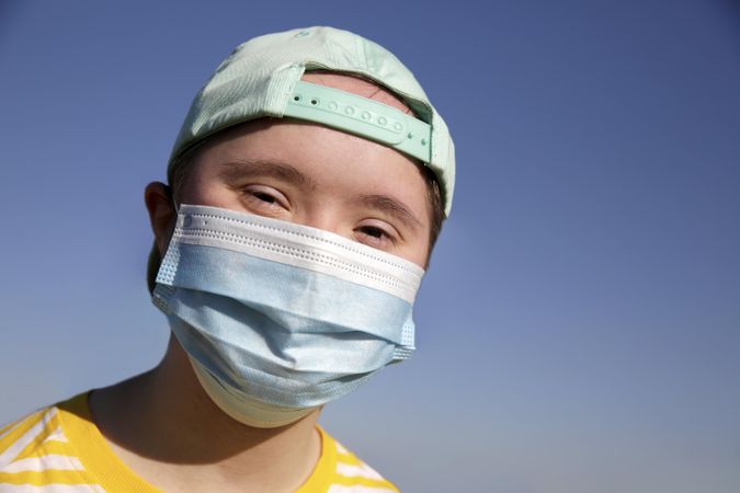 Young child wearing baseball cap and medical mask