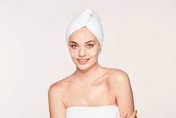 Delighted female with radiant skin applying cream