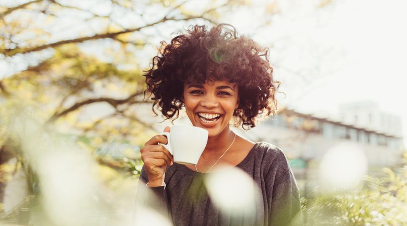 Close up of a woman with curly hair holding a coffee cup