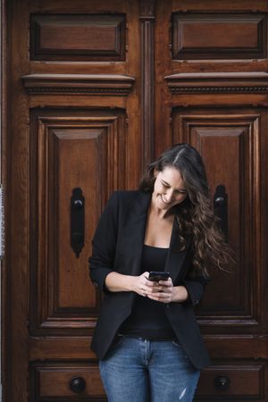 Young female using mobile phone on wooden door