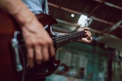 Man clamping strings on guitar neck
