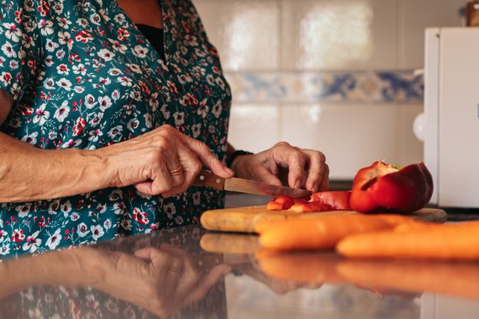 Mature woman cooking with peppers in the kitchen at home