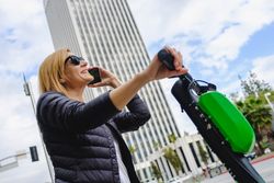 Woman talking on smartphone and riding electric scooter
