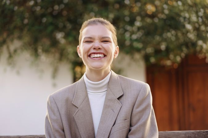A Smiling Young Woman in a Stylish Outfit Poses Gracefully Against a Natural Background