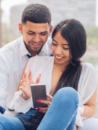 Man bonging smiling woman having fun with smartphone
