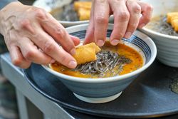 Cook preparing noodle soup with crispy chicken skin