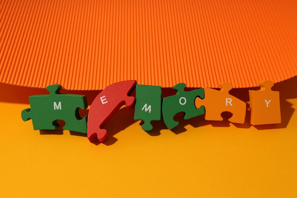 Orange paper flat lay with puzzle pieces spelling out the word “Memory”