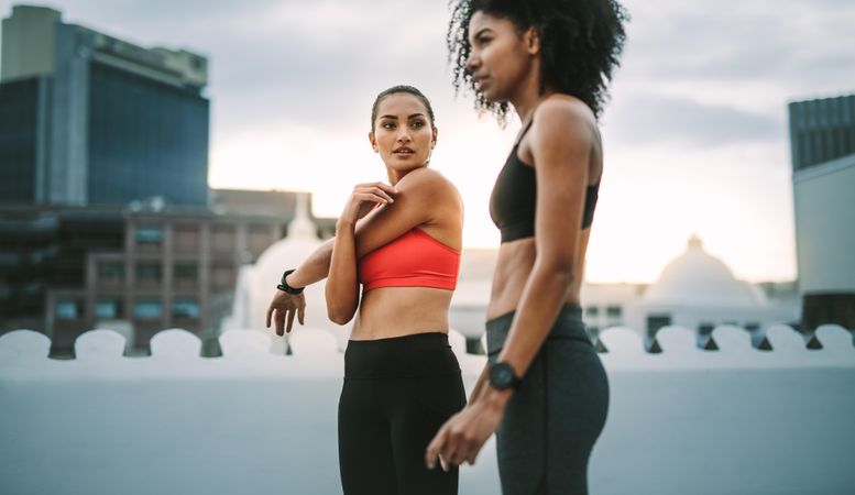 Two female athletes doing workout standing on rooftop