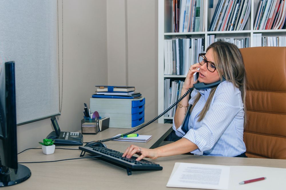 In demand businesswoman talking between two phones in office