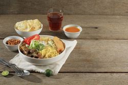 Dinner of Indonesian beef noodle soup with noodles, beef, spring roll, cabbage and tomato with copy space
