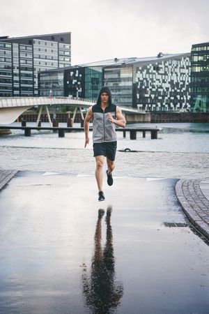 Muscular man in rain running in the rain