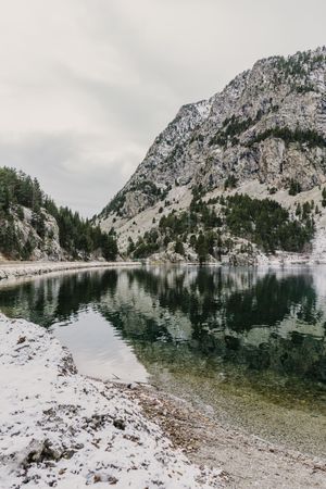 Wonderful lake between hills in snow and cloudy sky