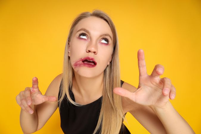 Concept of Halloween, young woman on yellow background