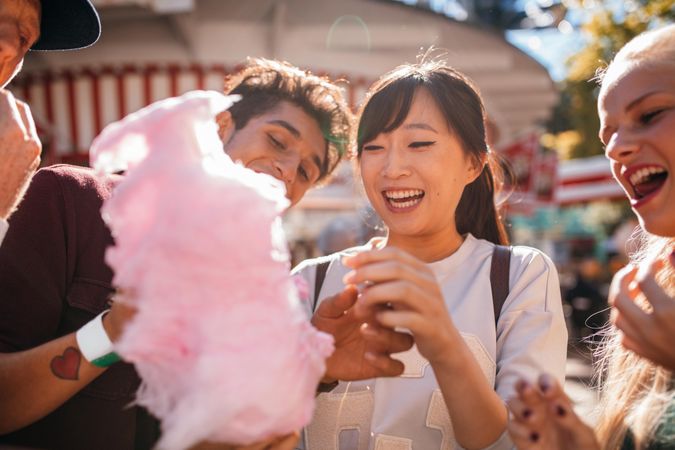 Smiling young people sharing cotton candy outdoors