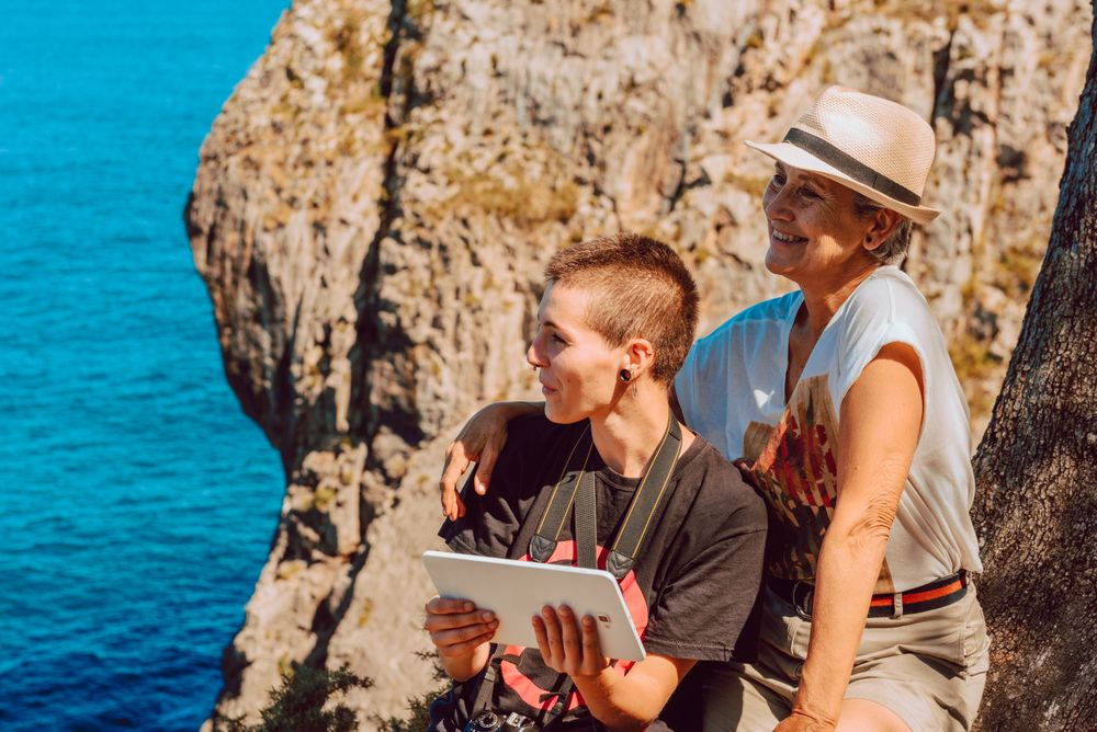 Mature woman with tablet in hands on rocky coast