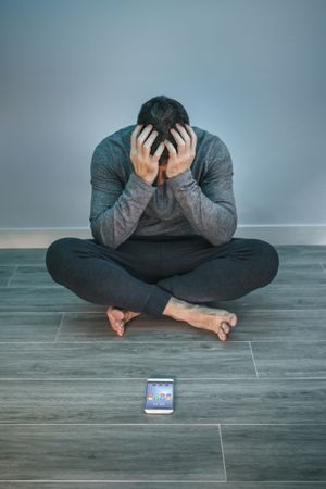 Man with problems sitting on the floor behind of his mobile