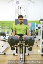 Fit male in green t-shirt working out quads using gym equipment 4mo2B0